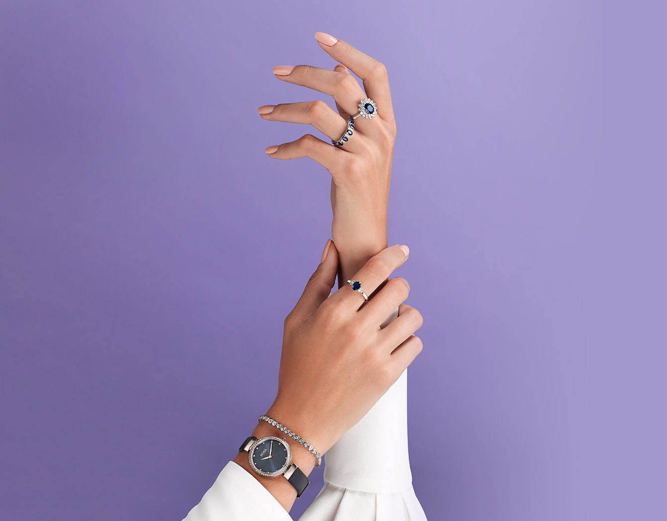 Sapphire rings on ladies hands. Wearing blue watch and white blouse